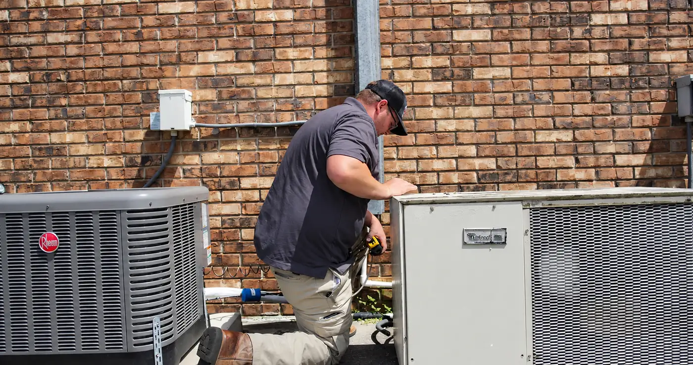 A technician working on the refrigerant line at an outdoor air conditioning unit