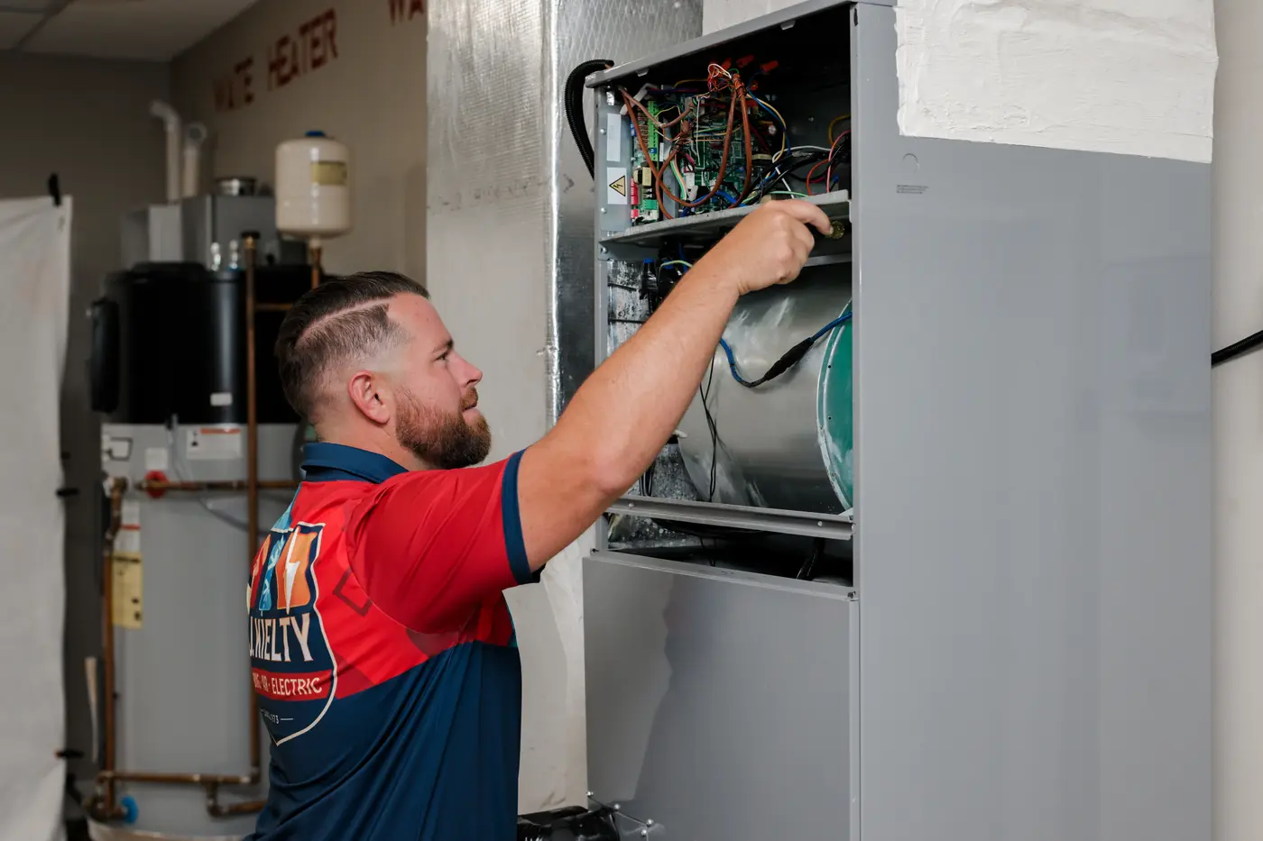 A technician servicing the electrical components inside an indoor air handler