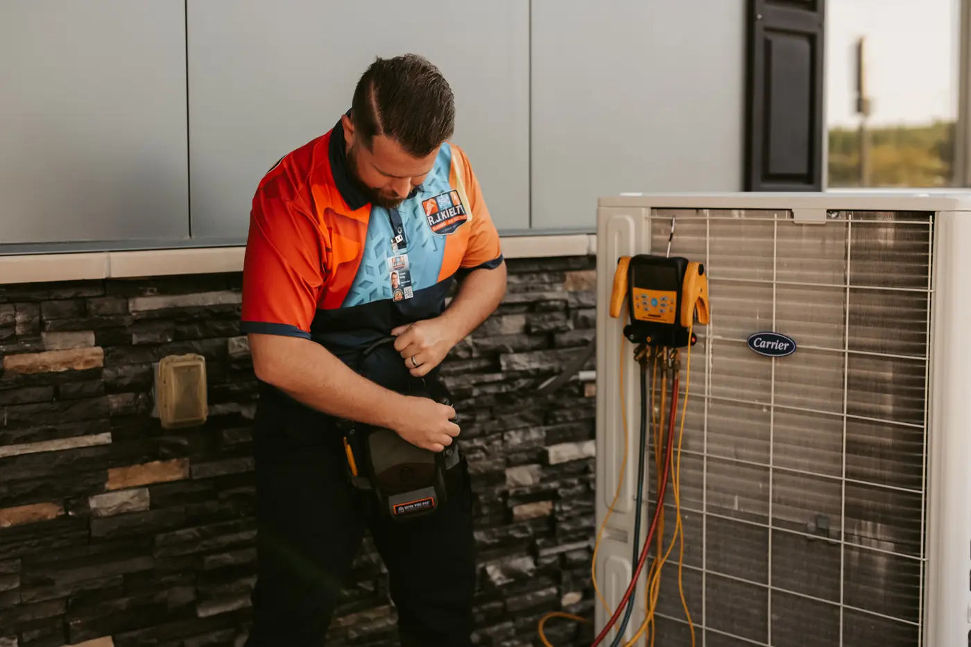 A technician packing up after completing diagnostic testing on an outdoor condenser